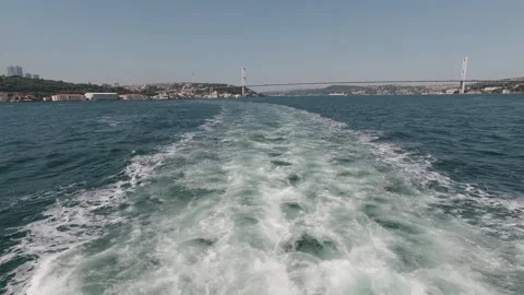Boat wake toward Bosphorus bridge and Istanbul skyline, clear day Stock Footage 320029528