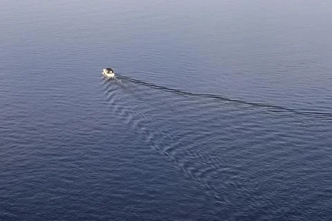 Boat wake on water surface in sunset light. Stock Photos