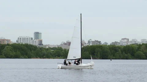A boat with a white sail floating on the lake under a clear sky. Stock Footage 198363229