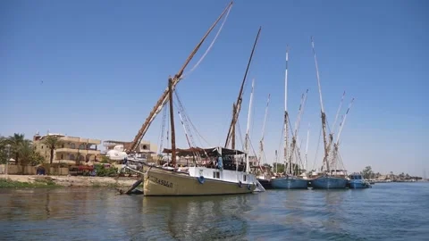 Boating Down The River Past A Group Of Moored Wooden Sailboats Stock Footage 226332323