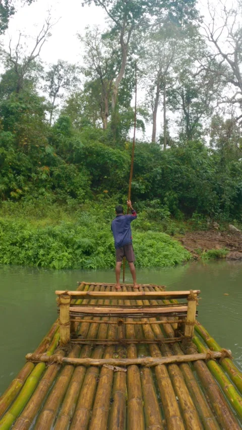 Boatman Navigating Bamboo Raft on Kanger Dhara River in Lush Green Forest Stock Footage 318569179