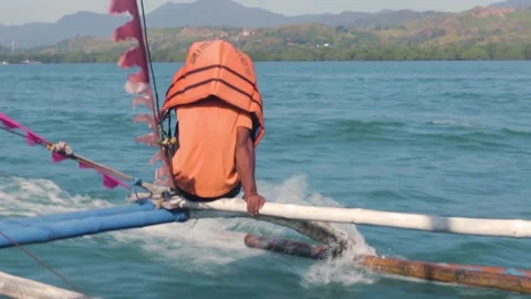 Boatman riding on outrigger of Asian native banca boat in the summer in Palawan Stock Footage 154833363