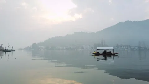 A boatman rowing a Shikara with a cloudy sky with rising sun reflecting on water Stock-Footage 240712824
