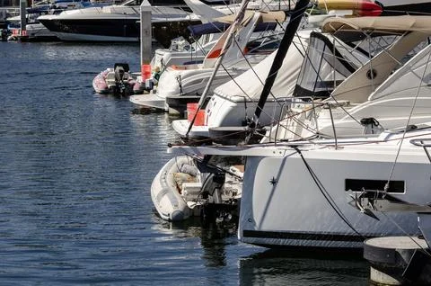Boats and floating docks reflected in calm marina water under bright sunlight Stock Photos