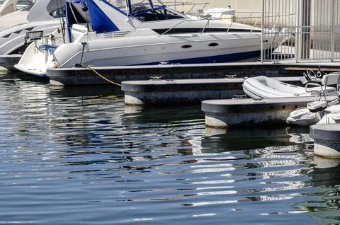 Boats and floating docks reflected in calm marina water under bright sunlig.. Stock-Fotos