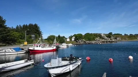 Boats float in calm water at a small harbor in Norway during sunny weather .. Stock Footage 340207667