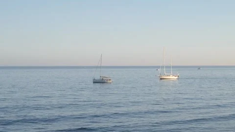 Boats float peacefully on calm sea under summer evening sunset Vídeos de archivo 300143341