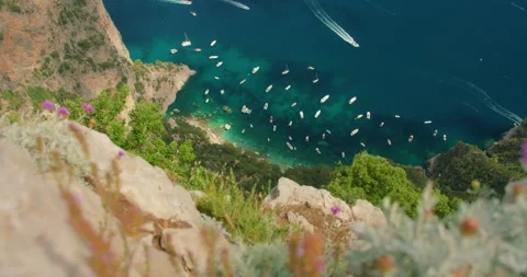 Boats floating below steep Capri cliffs in clear summer water seen from high Stock-Footage 343380793