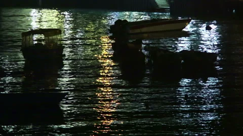 BOATS MOORED AT NIGHT WITH REFLECTIONS OF LIGHT FROM PIER Vidéo 32194335
