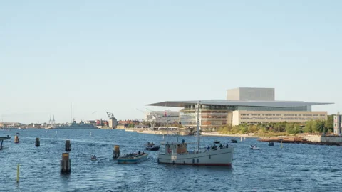 Boats navigate the inner harbor canal by Copenhagen Opera House landmark Stock Footage 345446230