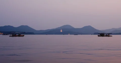 Boats pass by fish jumping out of West Lake during sunset in Hangzhou China Stock Footage 118472450
