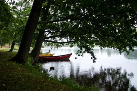 The boats in the river under the trees. Rainy summer day in Lithuania, Trakai Stock Photos