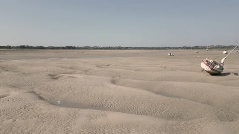 Boats stranded on river bed at low tide. Drone reveal shot, flying backwards. Stock Footage 220428176