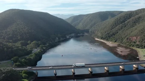 Boats under bridge over river with mountains in the background aerial wide Video stock 329105344