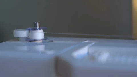 Bobbin being feed with new white thread on a sewing machine. Slow motion close Stock Footage 336183447