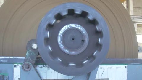 Bobbin of brown paper for making pulp cardboard boxes is spun on an industrial Video stock 232424210