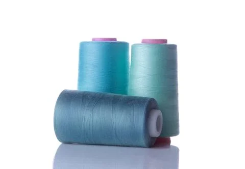 A bobbin with threads in blue tones on a white isolated background. accessori Stock Photos