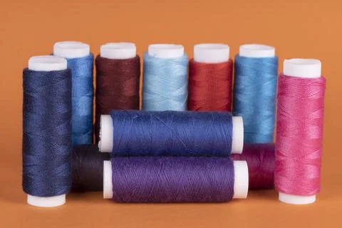 Bobbins of sewing thread of different colors isolated on orange Stock Photos