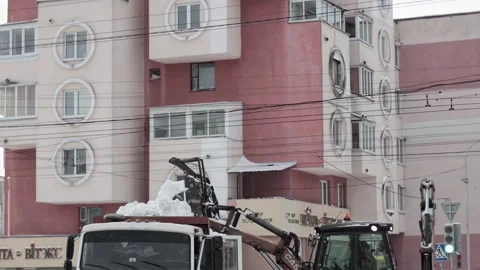 Bobruisk, Belarus 01.05.26: Loader machine fills truck with snow during snowfall Stock Footage 329214172