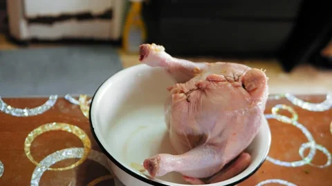 The body of the chicken sewn up with threads is in a dish on the table. 库存影片 197838631