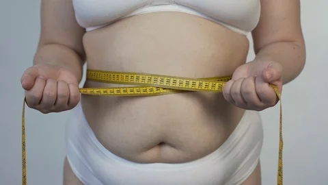 Body hatred, corpulent woman measuring her belly and tightening tape-line, diet Stock Footage