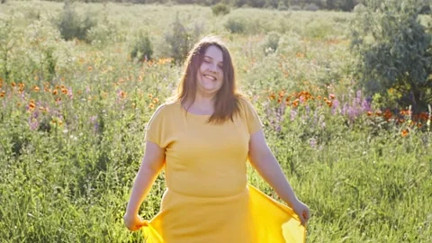Body positive young fat beautiful woman in a yellow dress dances against the Stock Footage 201199019