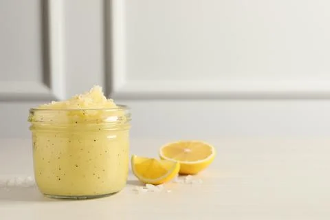 Body scrub in glass jar and lemon on light wooden table, space for text Stock Photos