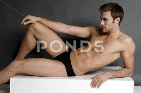 Body Shot Of An Athletic Young Man In A Black Bathing Trank, Lying