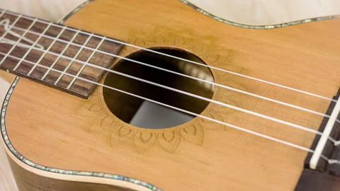 Body of a solid wood ukulele guitar on a yellow background. Stock Footage 111307394