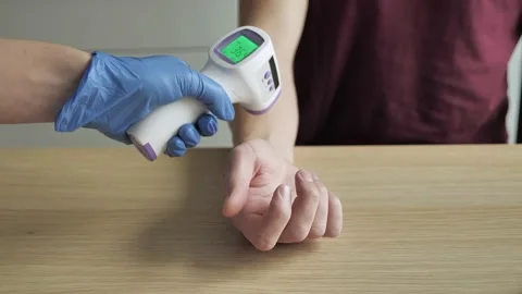 Body temperature diagnostics. A gloved hand holds a non-contact infrared thermom Stock Footage 144426292
