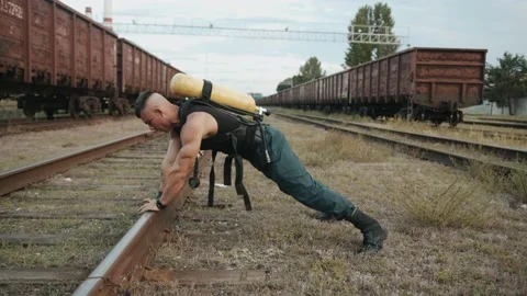 Bodybuilder with balloon dragger on the back is training at railway yard and 库存影片 218402763
