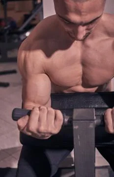 Bodybuilder,  bicep curl machine, close up, gym indooors. Stock Photos