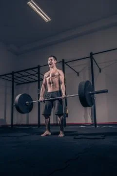 Bodybuilder deadlift, shouting screaming, weights bar barbell, dark gym indoo Stock Photos