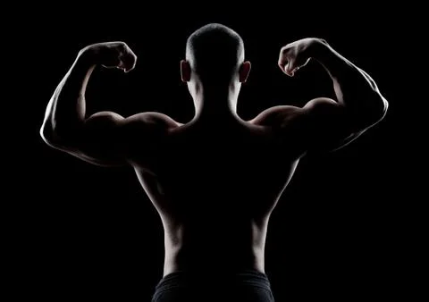 Bodybuilder demonstrates biceps back view on a dark background Stock Photos