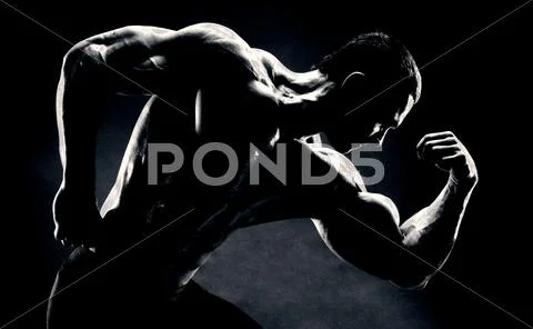 Bodybuilder demonstrates biceps on a dark background Stock Photos