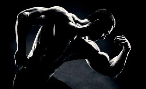 Bodybuilder demonstrates biceps on a dark background Stock Photos
