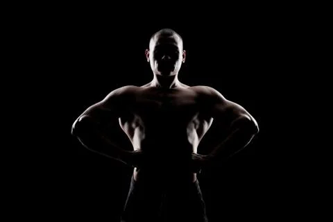 Bodybuilder demonstrates biceps on a dark background Stock Photos