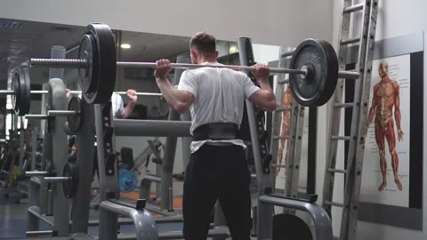 Bodybuilder does a squat with a barbell in the gym. View from behind Stock Footage 132172554