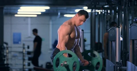 Bodybuilder doing an exercise with a barbell in the gym. exercises for muscles Video stock 80969451