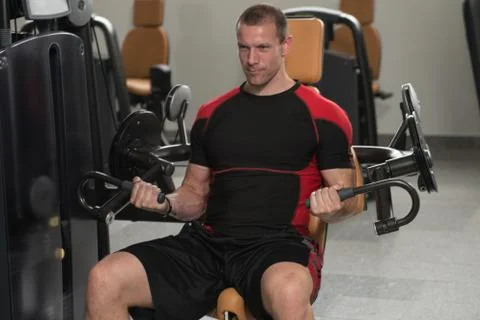 Bodybuilder Doing Exercise For Biceps On Machine Stock Photos