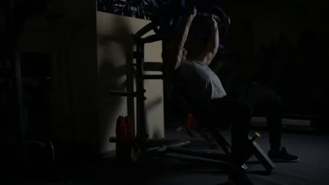 Bodybuilder doing exercise in darkened gym Video stock 76168230