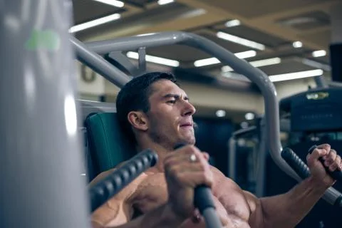 Bodybuilder doing hard exercise. The  work in the gym Stock Photos
