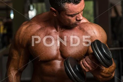Bodybuilder doing heavy weight exercise for biceps with dumbbell Stock Photos