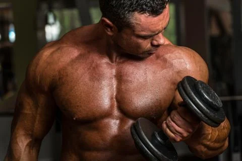 Bodybuilder doing heavy weight exercise for biceps with dumbbell Stock Photos