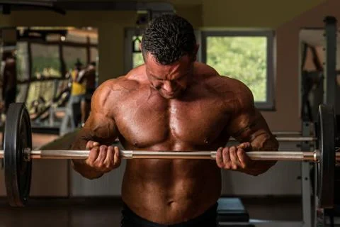 Bodybuilder doing heavy weight exercise for biceps with barbell Foto stock