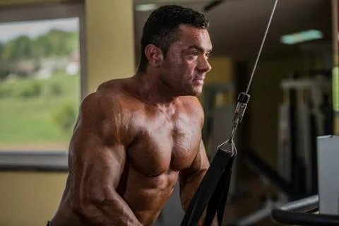 Bodybuilder doing heavy weight exercise for triceps with cable Stock Photos