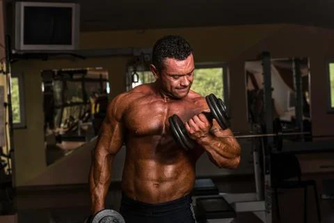 Bodybuilder doing heavy weight exercise for biceps with dumbbell Stock Photos