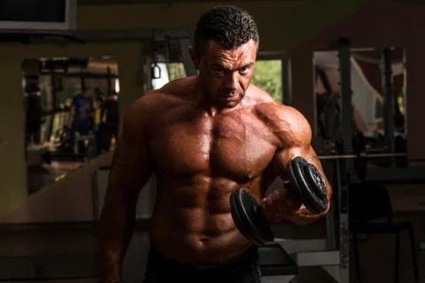 Bodybuilder doing heavy weight exercise for biceps with dumbbell Stock Photos