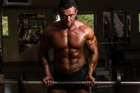 Bodybuilder doing heavy weight exercise for biceps with barbell Stock Photos