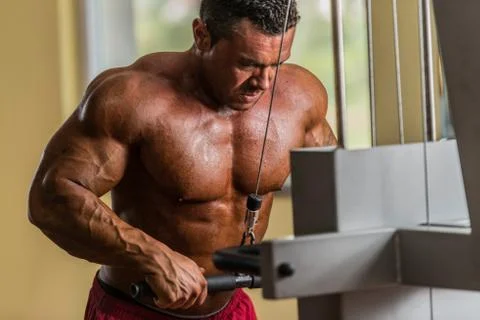 Bodybuilder doing heavy weight exercise for triceps with cable Stock Photos